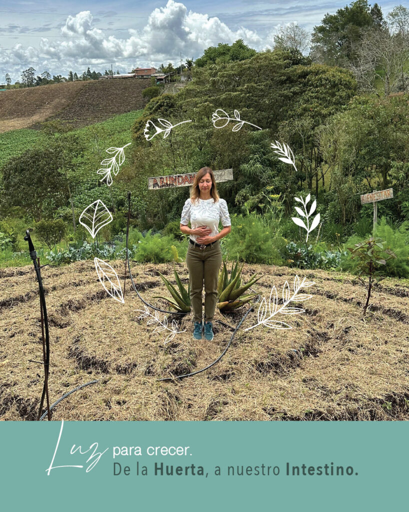 Dra. Luz Elena Salazar en una huerta natural rodeada de plantas, representando la conexión entre alimentación, bienestar digestivo y medicina funcional.